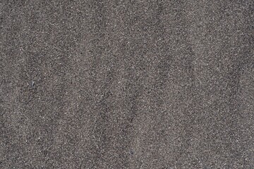 A beach with black volcanic sand, natural sand ripples and an ocean horizon