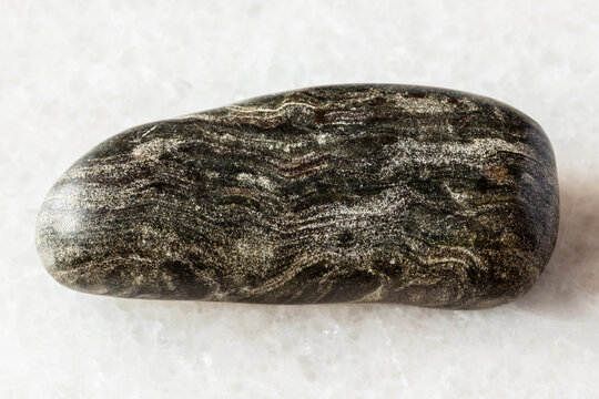 sample of tumbled phyllite rock on white marble