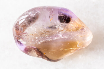 sample of tumbled ametrine mineral on white marble