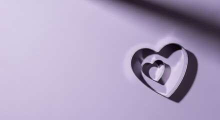 Two nested heart-shaped cookie cutters on a soft purple background hearts love