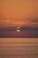 Vertical sea view and the sun hidden behind the clouds during a