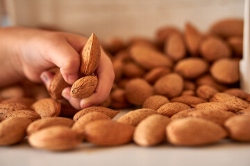 Closeup shot of almond nuts on human hand.