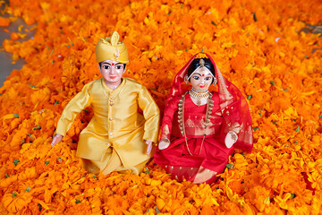 Traditional Indian Wedding Dolls Dressed in Vibrant Festive Attire Surrounded by a Bed of Marigold...