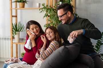 Happy family with pregnant mother sitting on sofa, having fun with joyful kid, waiting for baby