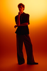 Stylish young man showcases modern fashion against a warm gradient backdrop