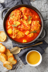 Chicken Bouillabaisse with Rouille and bread closeup in the plate on the table. Vertical top view from above