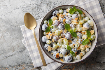 Fresh sweet Sultana grape salad with almond flakes, mint, Greek yogurt and cream cheese dressing close-up in a plate on the table. Horizontal top view from above