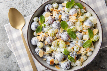 Sultana grape salad with almond flakes, mint, Greek yogurt and cream cheese dressing close-up in a plate on the table. Horizontal top view from above