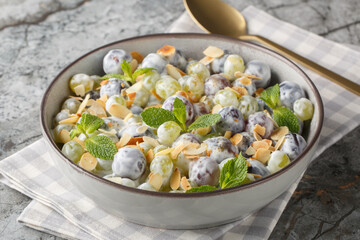 Light dessert grape salad with almonds, mint and yogurt dressing close-up in a plate on the table. Horizontal