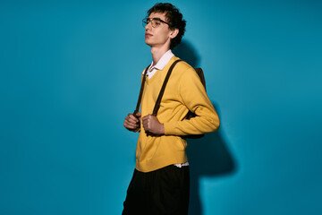 Stylish young man confidently poses against a vibrant blue backdrop in trendy attire