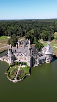 Aerial view of the Chateau de la Bretesche surrounded by water, with lush green trees in the background, Missillac, Pays de la Loire, France.