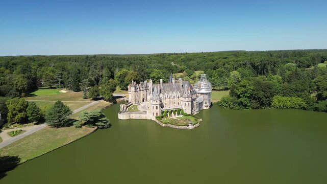 Aerial view of the elegant La Bretesche castle surrounded by a wide moat reflecting the architectural details, Missillac, Pays de la Loire, France.