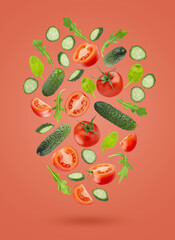 Fresh vegetable salad ingredients - red tomatoes, green cucumbers, green leaves -  fly or fall as art flow composition on pink background. Summer healthy food vegetables for detox menu, fitness meal.