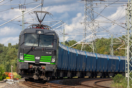 Ein elektrisch betriebener G&uuml;terzug, gezogen von einer Siemens Vectron-Lokomotive der Baureihe 193 (193 209) der ELL &ndash; European Locomotive Leasing &ndash;, durchf&auml;hrt eine Kurve.