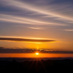 A breathtaking sunset view reveals a vibrant, golden sun sinking below a horizon line of dark silhouettes.