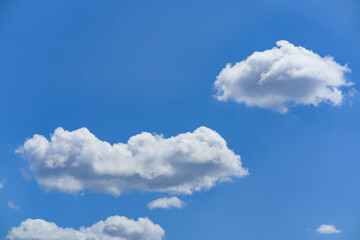 Fluffy white clouds floating in a clear blue sky during a sunny day