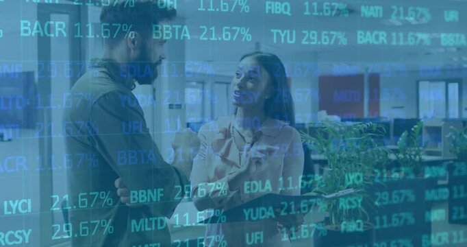 Woman tapping tablet screen showing financial figures updating for analysis while colleague nodding