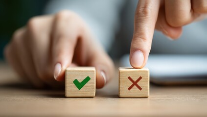A hand pointing to two wooden blocks with a green checkmark and a red X sign on a desk