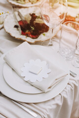 Elegant table setting with a beautiful guest favor, featuring a small chocolate on a decorative paper flower and a linen napkin, creating a warm and inviting atmosphere for a special celebration