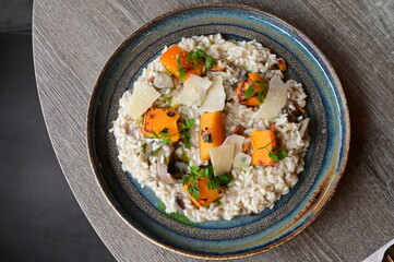 Creamy mushroom risotto served with roasted pumpkin and fresh herbs on a rustic plate.