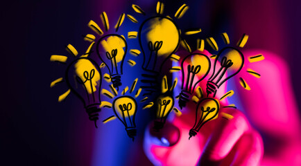 Stock photo of hand drawing glowing lightbulbs, symbolizing ideas, innovation, and creative solutions.