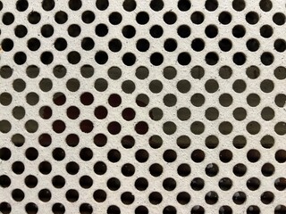 Close-up of perforated metal surface with symmetrical circular holes and shadow variations – ideal industrial texture for engineering, ventilation systems, or design backgrounds.