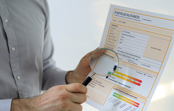 Close-up of hands holding energy performance certificate and magnifying glass.  Ideal for energy efficiency, sustainability, and real esta