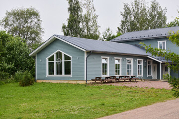 Contemporary Blue Wooden House Featuring Large Windows and a Cozy Outdoor Seating Area