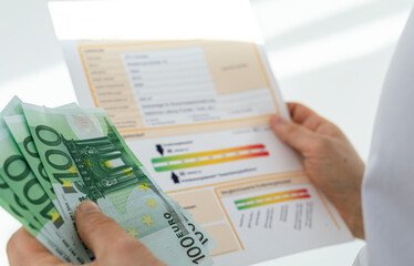 Obraz premium Close-up of hands holding euro banknotes and examining a financial document with charts and graphs.