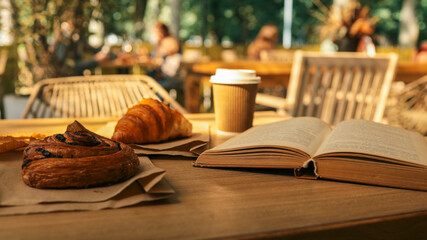Relaxing outdoor cafe scene with pastries, coffee, and a book.