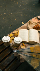 Autumn scene with coffee, book, and croissant on a bench