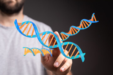 Abstract image of a man interacting with a 3D model of a DNA helix. Ideal for science, technology, and medicine.