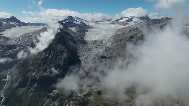 Aerial view of snow covered mountains with clouds and rocky terrain creating a stunning contrast of white and grey, Brescia, BS, Italia.