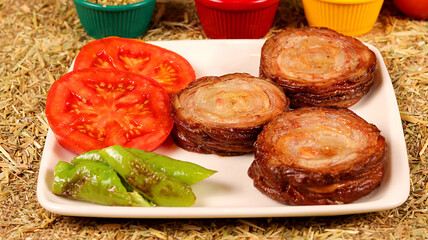 3 kokoreç and peppers and tomatoes on a white plate, cut into one portion