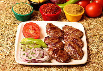a serving of grilled meatballs with vegetables and spices on a white plate