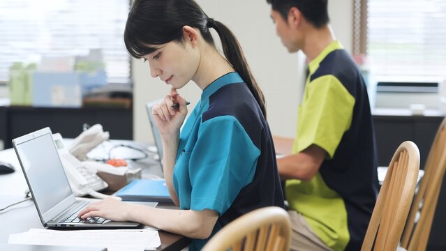 事務仕事をするアジア人介護士 - Powered by Adobe