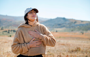 Young woman breathing fresh air in the autumn mountain 