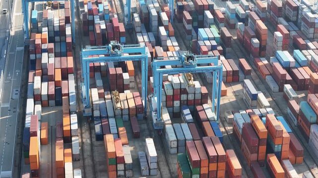 Vado Gateway, Italy - 21 September 2025: Aerial view of rows upon rows of stacked cargo containers, creating a colorful, textured landscape with gantry cranes.