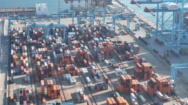 Vado Gateway, Italy - 21 September 2025: Aerial view of neatly stacked cargo containers, creating a vibrant mosaic of colors and patterns under gantry cranes.