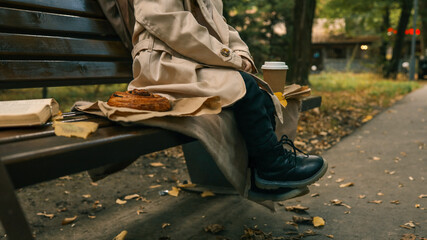 Person enjoying a peaceful moment on a park bench with coffee and pastry.