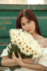 Close up portrait of young woman with bouquet of daisies outdoors