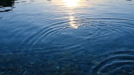 the visual and auditory beauty of water ripples and light reflections on a calm water surface