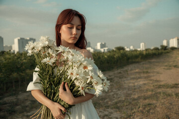 Close up portrait of young woman with bouquet of daisies outdoors