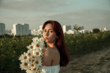 Close up portrait of young woman with bouquet of daisies outdoors