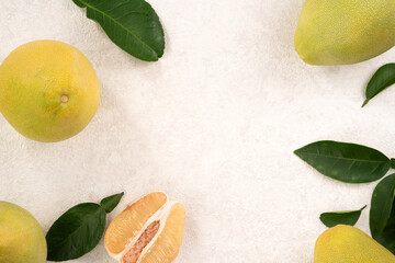 Fresh pomelo fruit with leaf on white table background.