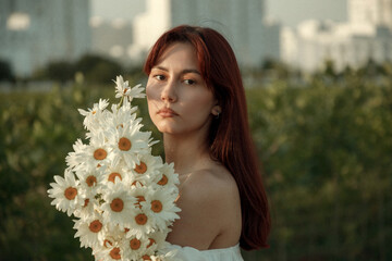 Close up portrait of young woman with bouquet of daisies outdoors