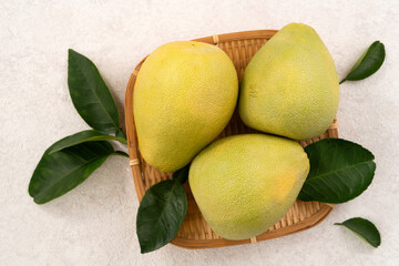 Fresh pomelo fruit with leaf on white table background.