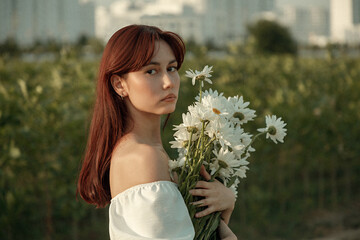 Close up portrait of young woman with bouquet of daisies outdoors
