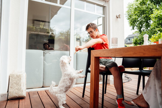 Teenage boy with trisomy 21 bonding with small dog and family outdoors
