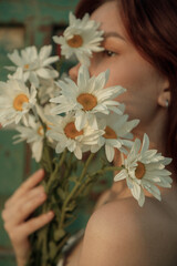 Close up portrait of young woman with bouquet of daisies outdoors